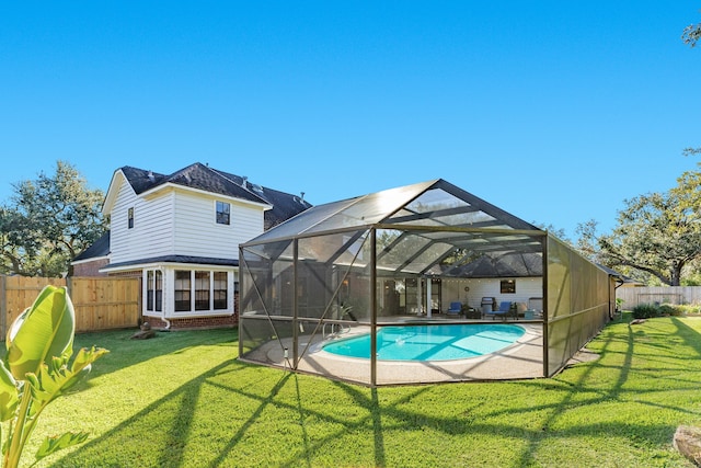 view of swimming pool featuring glass enclosure and a lawn