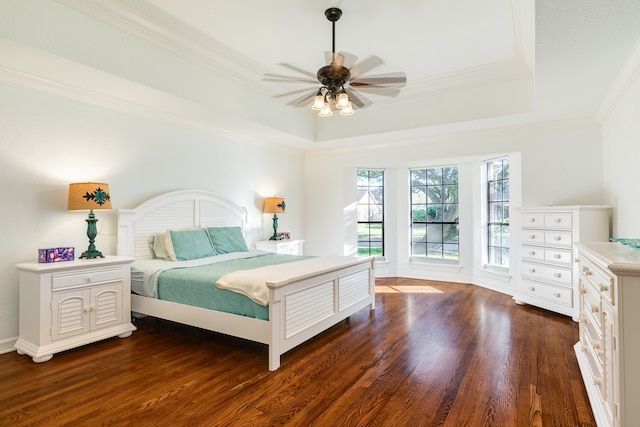 bedroom featuring ceiling fan, crown molding, dark wood-type flooring, and a tray ceiling