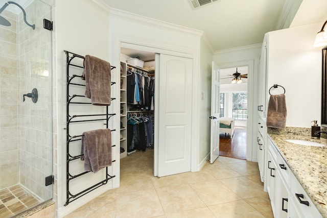 bathroom with vanity, crown molding, tile patterned flooring, ceiling fan, and tiled shower