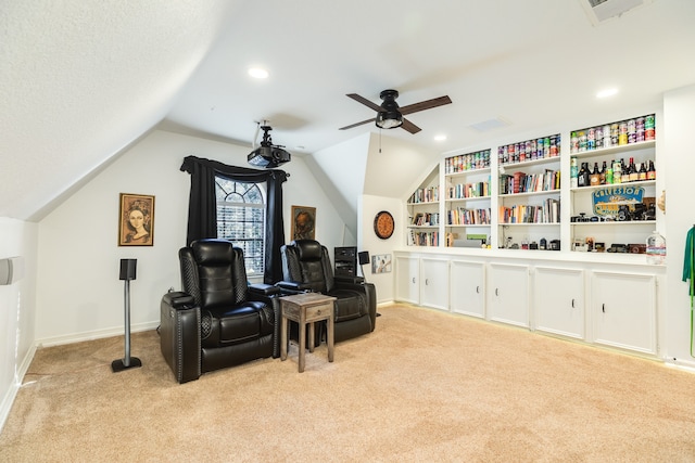 sitting room featuring ceiling fan, built in features, light colored carpet, and lofted ceiling