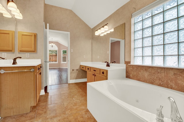 bathroom with vanity, vaulted ceiling, a notable chandelier, and a tub to relax in