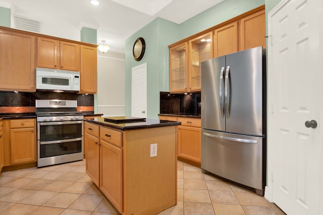 kitchen with appliances with stainless steel finishes, decorative backsplash, a center island, and light tile patterned floors