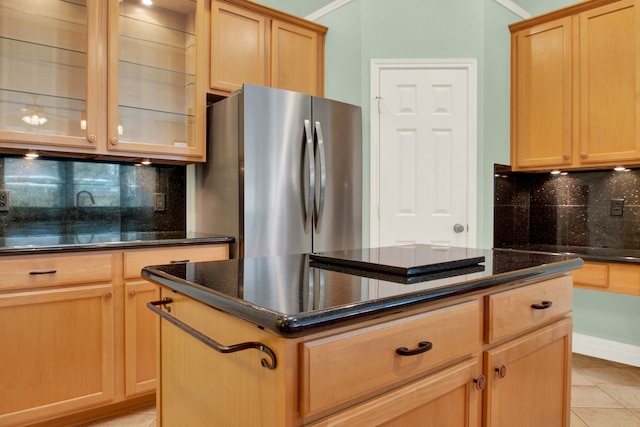 kitchen with a kitchen island, backsplash, light tile patterned floors, light brown cabinetry, and stainless steel refrigerator