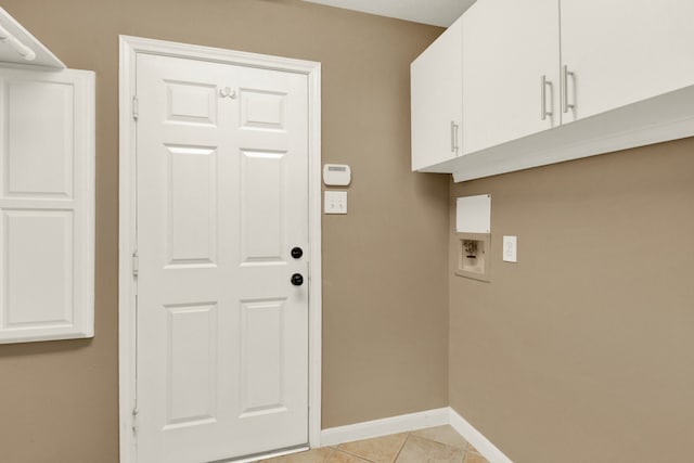 washroom with washer hookup, light tile patterned floors, and cabinets