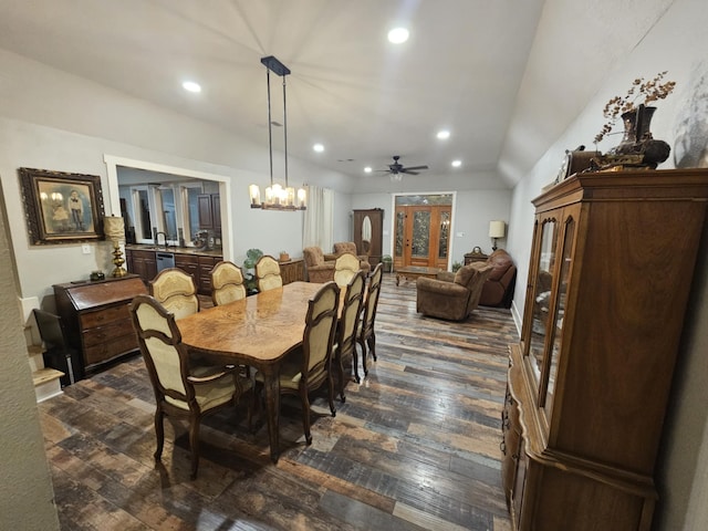 dining area with dark wood-type flooring, ceiling fan with notable chandelier, and vaulted ceiling