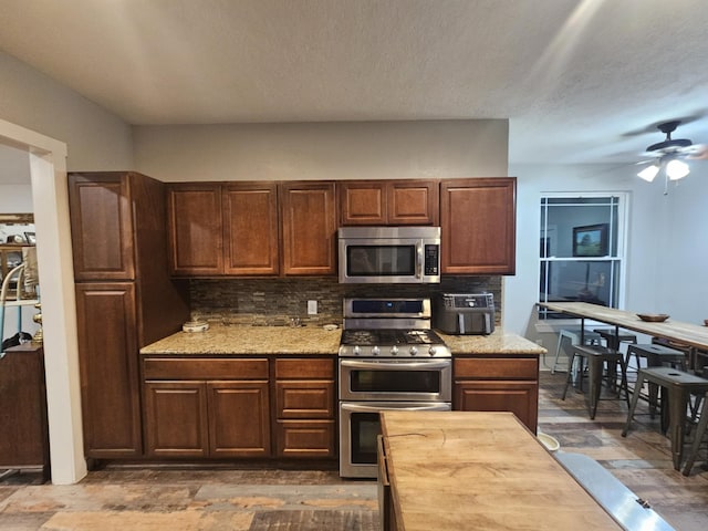 kitchen featuring appliances with stainless steel finishes, decorative backsplash, ceiling fan, and a textured ceiling