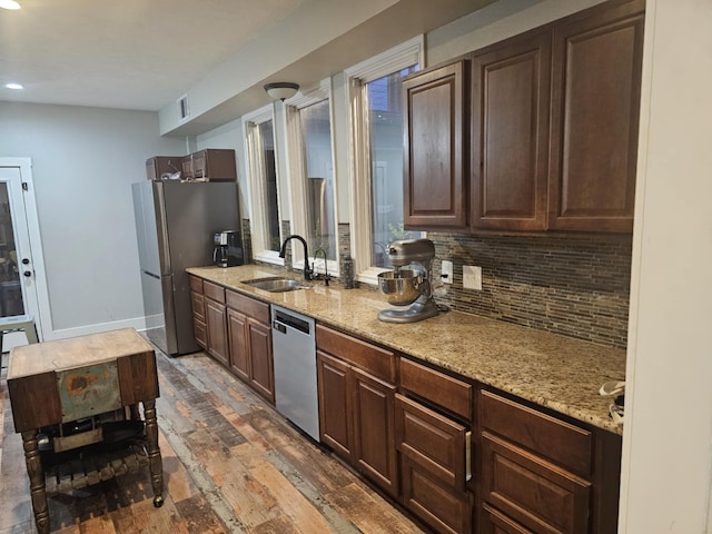 kitchen featuring light stone counters, stainless steel appliances, dark brown cabinetry, dark hardwood / wood-style flooring, and sink