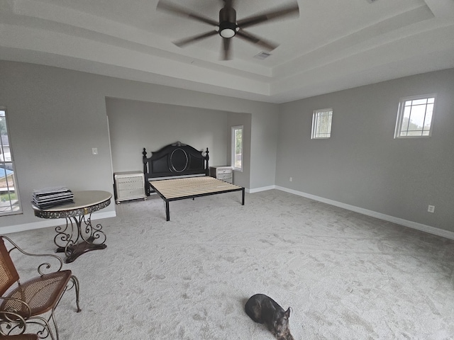 sitting room with ceiling fan, light colored carpet, a healthy amount of sunlight, and a tray ceiling