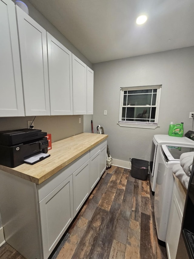 clothes washing area with washing machine and clothes dryer, cabinets, and dark wood-type flooring