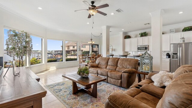 living room with ornate columns, crown molding, ceiling fan with notable chandelier, and light tile patterned floors