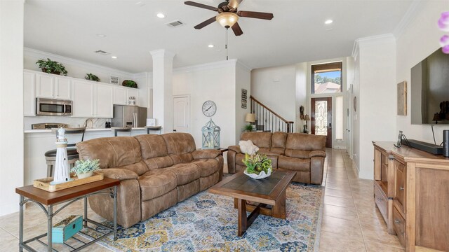 tiled living room with crown molding, ornate columns, and ceiling fan