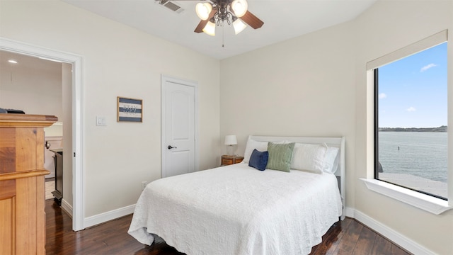 bedroom featuring dark hardwood / wood-style floors, a water view, and ceiling fan