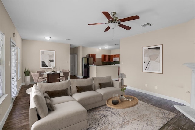 living room with dark wood-type flooring and ceiling fan