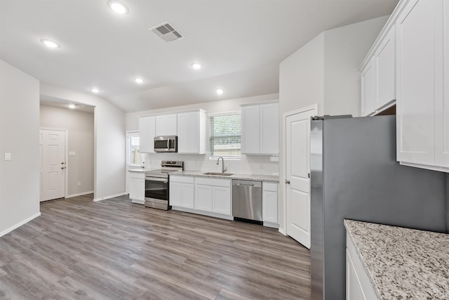 kitchen with sink, appliances with stainless steel finishes, white cabinets, and light hardwood / wood-style floors