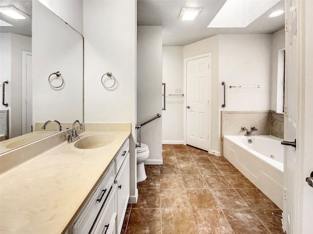 bathroom with tile patterned flooring, a skylight, vanity, toilet, and a bathtub