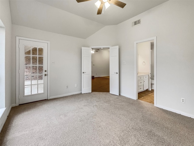 unfurnished bedroom featuring ensuite bathroom, light carpet, ceiling fan, and vaulted ceiling