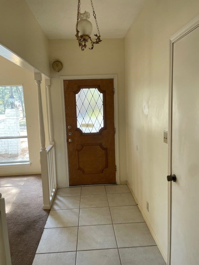 entryway with decorative columns, a wealth of natural light, and light tile patterned flooring