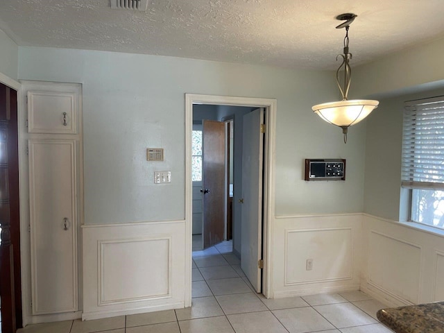 unfurnished dining area featuring light tile patterned flooring and a textured ceiling