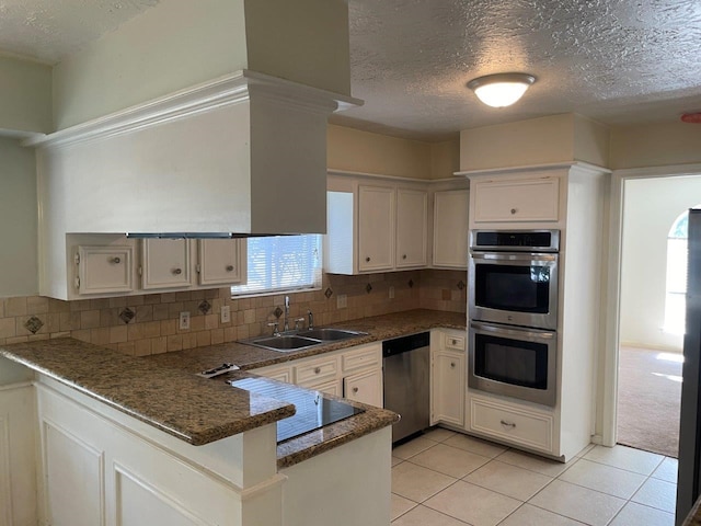 kitchen featuring white cabinets, kitchen peninsula, sink, backsplash, and appliances with stainless steel finishes