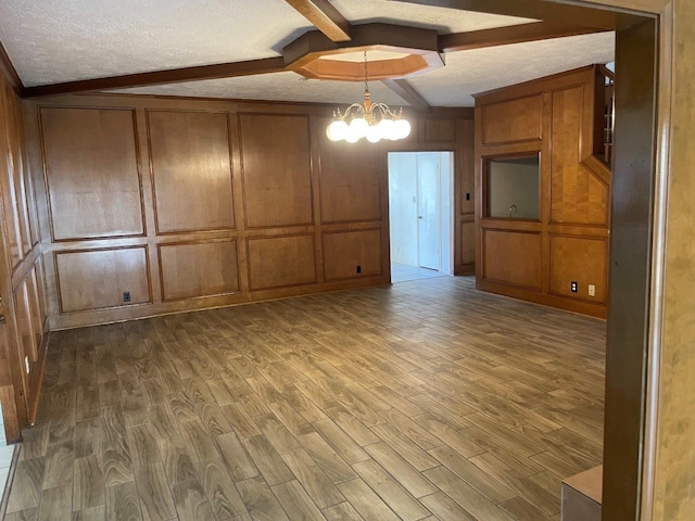 interior space featuring hardwood / wood-style floors, wood walls, a textured ceiling, and a chandelier