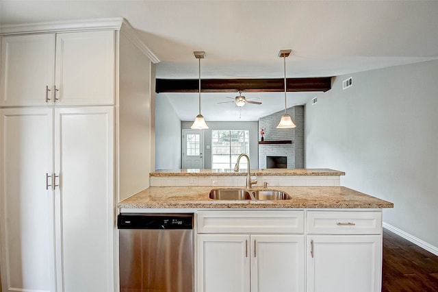 kitchen featuring stainless steel dishwasher, white cabinetry, sink, and a brick fireplace