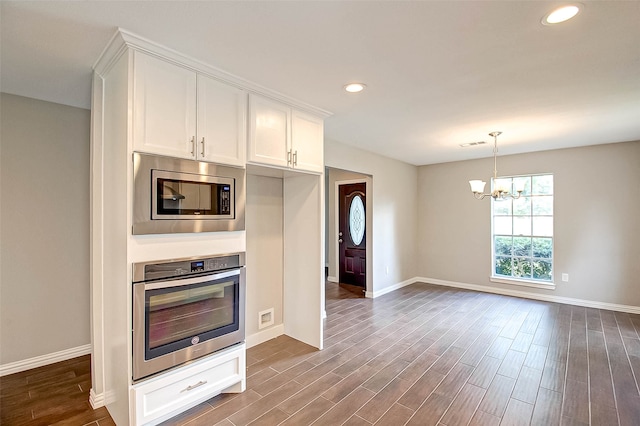 kitchen with appliances with stainless steel finishes, pendant lighting, a notable chandelier, dark hardwood / wood-style floors, and white cabinetry