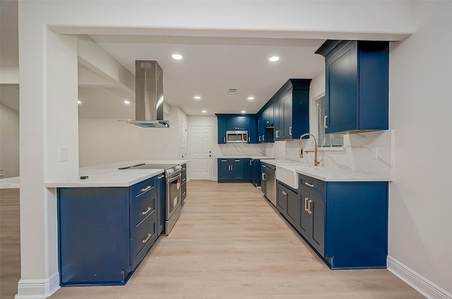 kitchen with decorative backsplash, wall chimney exhaust hood, light hardwood / wood-style flooring, blue cabinetry, and appliances with stainless steel finishes