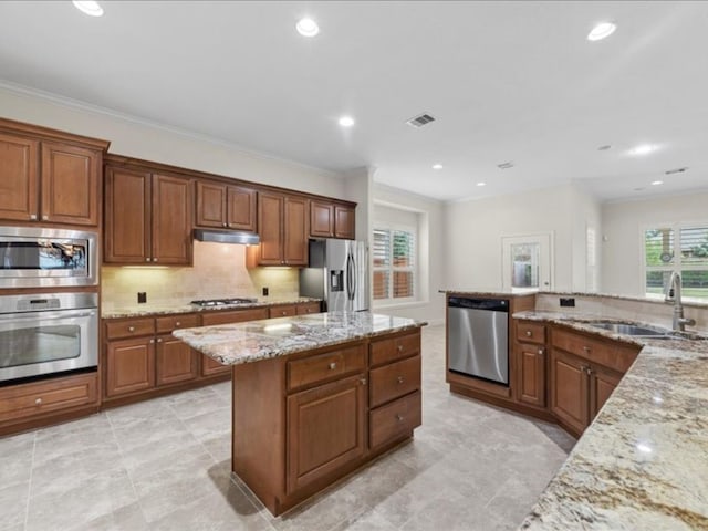 kitchen with decorative backsplash, appliances with stainless steel finishes, light stone countertops, crown molding, and sink