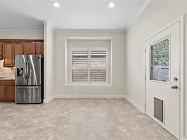 kitchen featuring crown molding, stainless steel fridge, tasteful backsplash, and light stone countertops