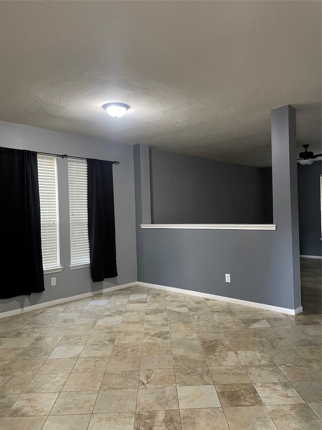 empty room with ceiling fan and a textured ceiling