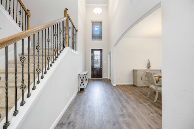 entrance foyer with a towering ceiling, hardwood / wood-style flooring, and crown molding