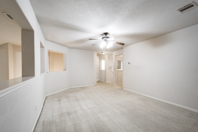 carpeted spare room with ceiling fan and a textured ceiling