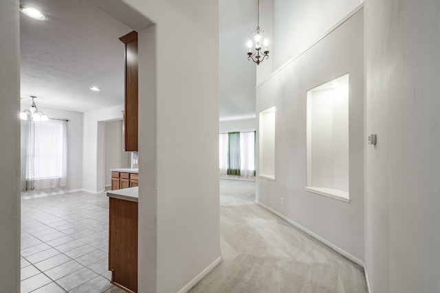 hall featuring light carpet, an inviting chandelier, and plenty of natural light