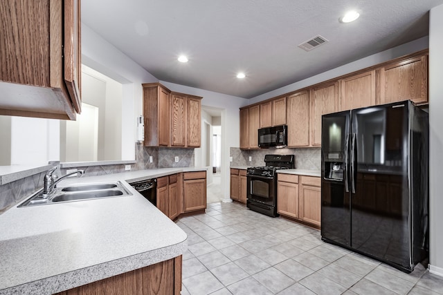 kitchen with light tile patterned floors, tasteful backsplash, black appliances, and sink