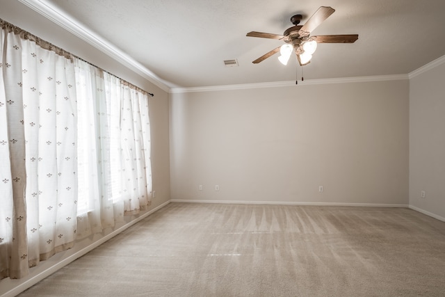 spare room featuring crown molding, a healthy amount of sunlight, and light colored carpet