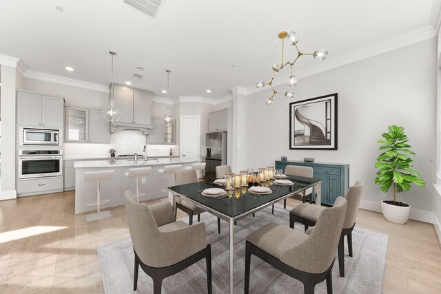 dining area with light hardwood / wood-style flooring, ornamental molding, and sink