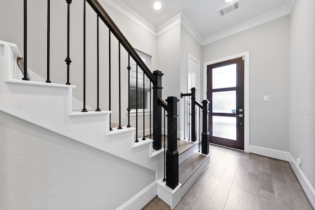 entryway with ornamental molding and hardwood / wood-style flooring