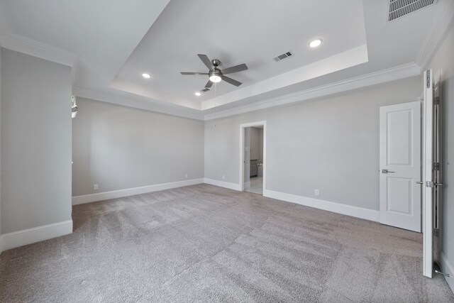 carpeted spare room featuring ceiling fan, a raised ceiling, and ornamental molding