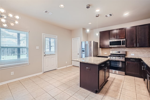 kitchen featuring light stone countertops, dark brown cabinets, a center island, hanging light fixtures, and stainless steel appliances