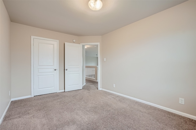 unfurnished bedroom with light carpet and a closet