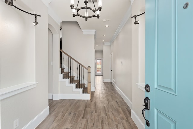 entrance foyer featuring light hardwood / wood-style floors, a notable chandelier, and ornamental molding