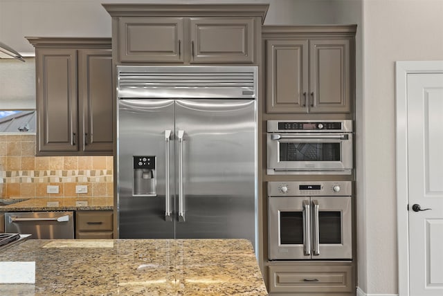 kitchen featuring light stone countertops, appliances with stainless steel finishes, and backsplash