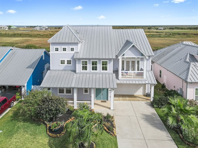 view of front of home with concrete driveway, an attached garage, a standing seam roof, metal roof, and a balcony