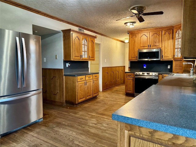 kitchen with crown molding, sink, hardwood / wood-style floors, appliances with stainless steel finishes, and a textured ceiling