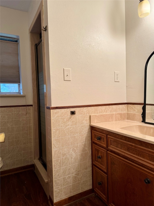 bathroom featuring vanity, walk in shower, toilet, and tile walls