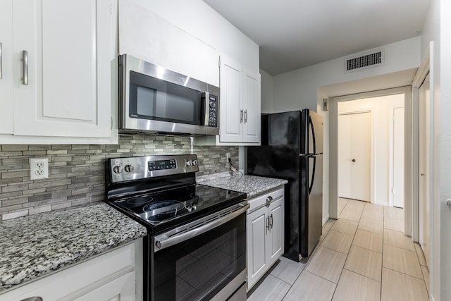 kitchen with white cabinets, light stone countertops, stainless steel appliances, and tasteful backsplash