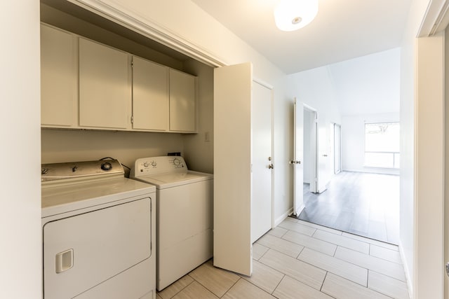 clothes washing area featuring washing machine and dryer and cabinets