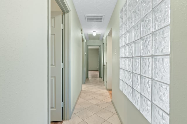 corridor featuring light tile patterned floors and a textured ceiling