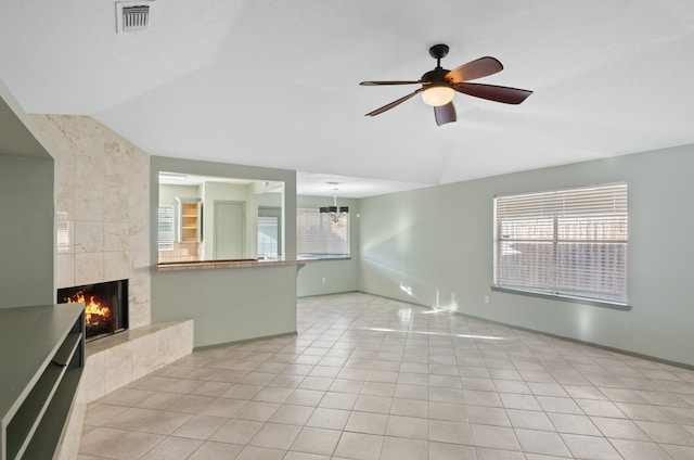 unfurnished living room featuring light tile patterned floors, ceiling fan with notable chandelier, vaulted ceiling, and a tiled fireplace