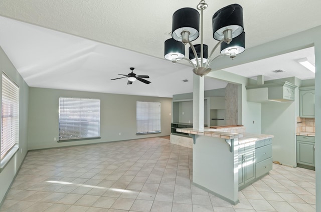 kitchen with backsplash, ceiling fan, light tile patterned floors, tile countertops, and a breakfast bar area